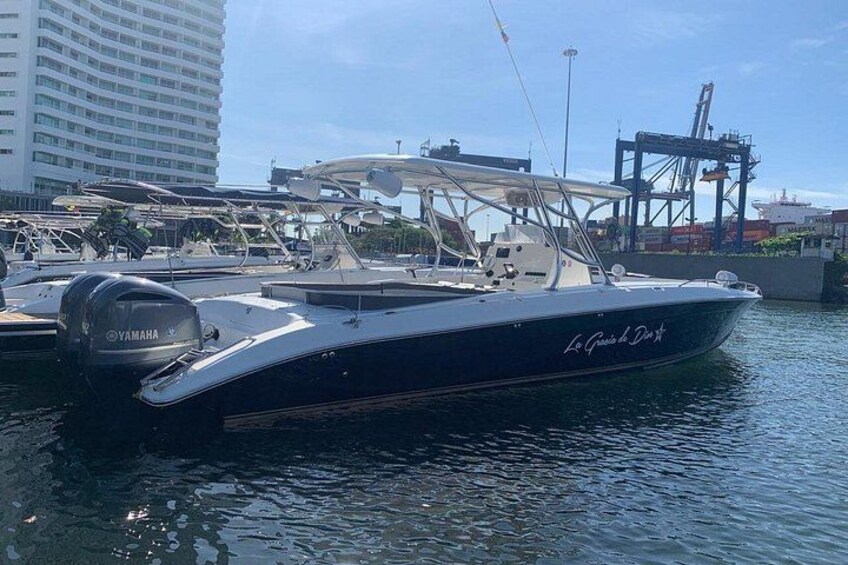 Eine Yacht namens 'La Guitare de Dix' liegt in einer Marina vor, im Hintergrund sind ein großes Gebäude und Kräne zu sehen. 1