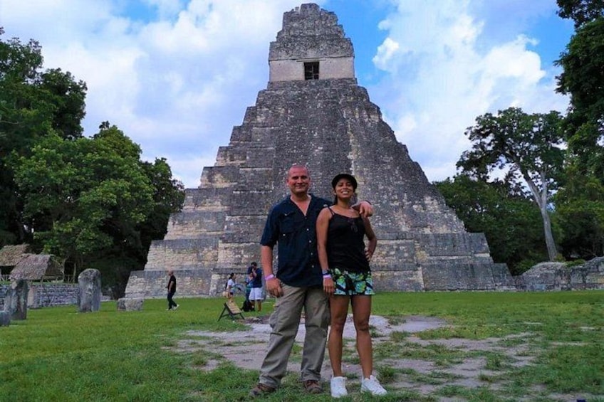 En stor, forntida pyramidliknande byggnad med en vuxen och ett barn framför. 1