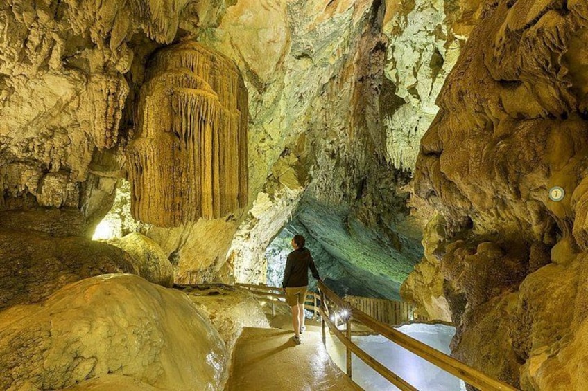 A cave with stalactites, a person walking, and a staircase. 1