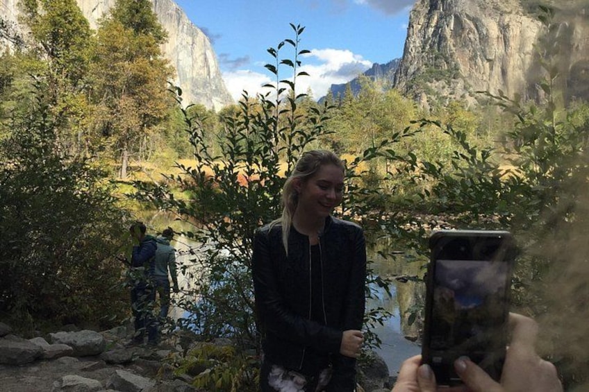 Eine Person macht mit einem Smartphone ein Foto in einer bergigen Landschaft mit Bäumen und einem Fluss. 4