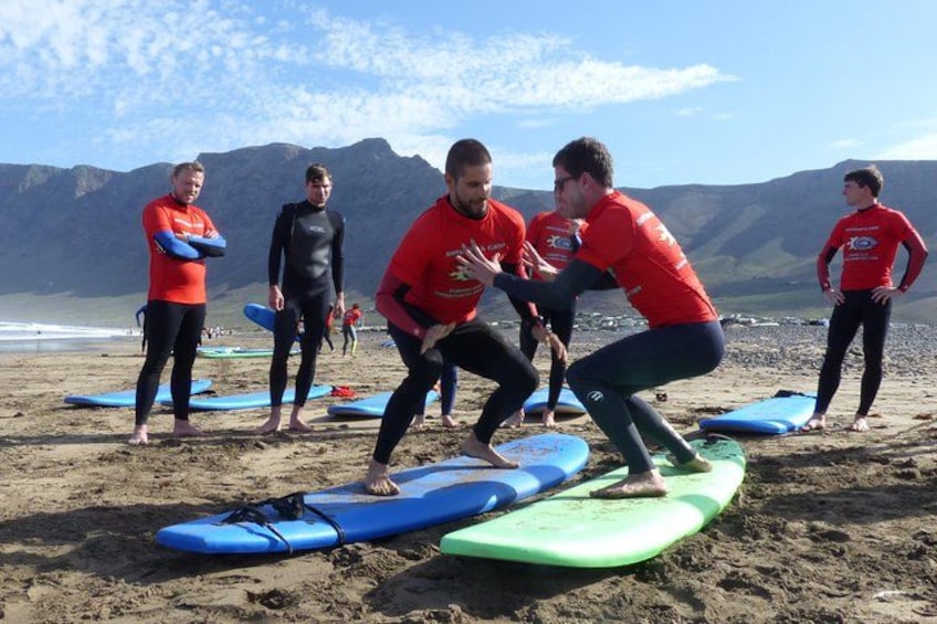 Des personnes font de la planche à voile sur une plage, avec des planches à voile et des montagnes en arrière-plan. 2