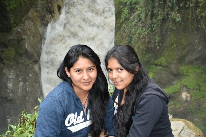 Two individuals in front of a waterfall with greenery around. 4