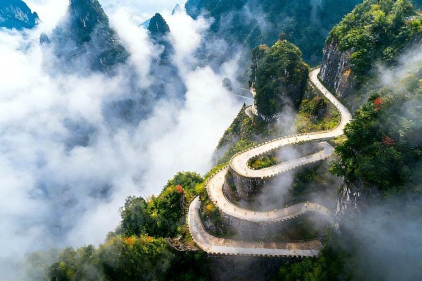 A winding mountain road surrounded by lush greenery and misty clouds. 2