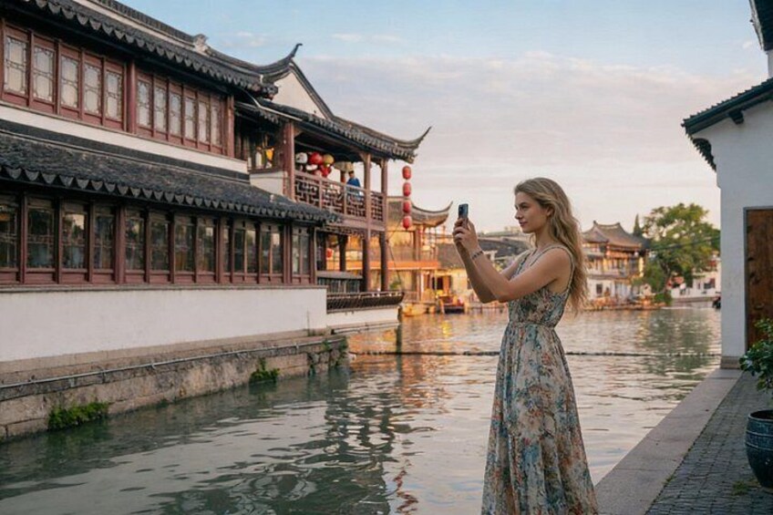 A woman taking a photo of traditional architecture by a canal. 1