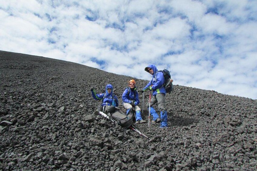 Tres excursionistas en una ladera rocosa bajo un cielo nublado. 4