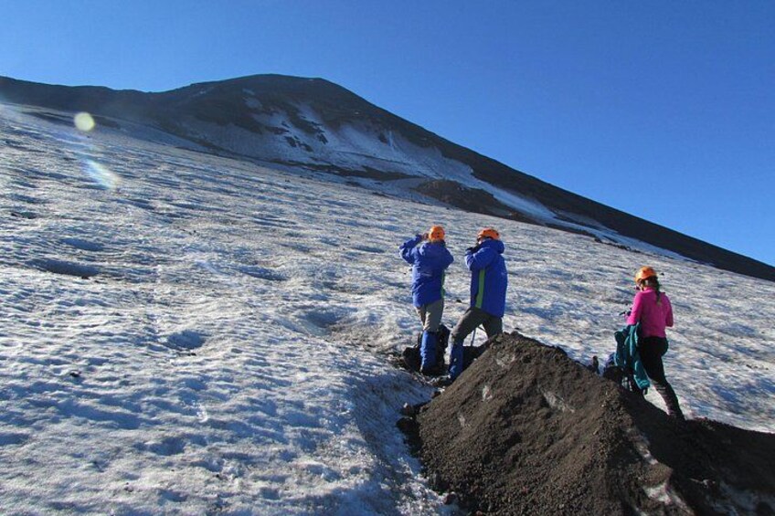 Tres personas hacen senderismo en una montaña nevada con cielo despejado. 2