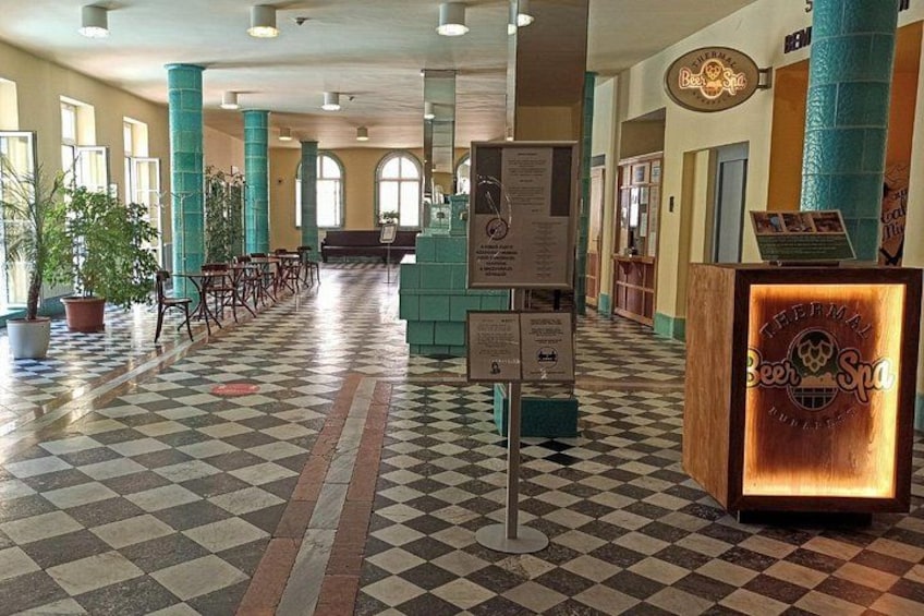 A lobby with checkered flooring, teal pillars, and a sign for a beer and spa. 3