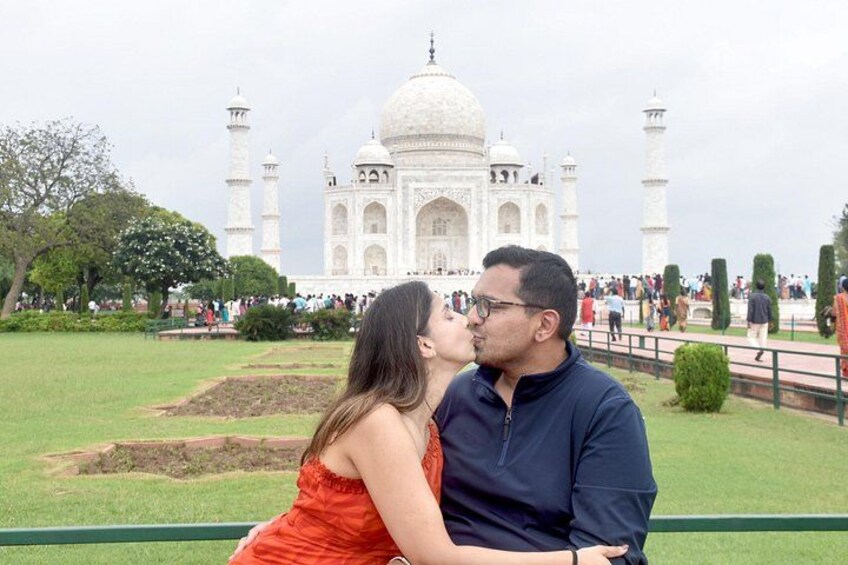 A couple kissing in front of the Taj Mahal with the monument in the background. 5
