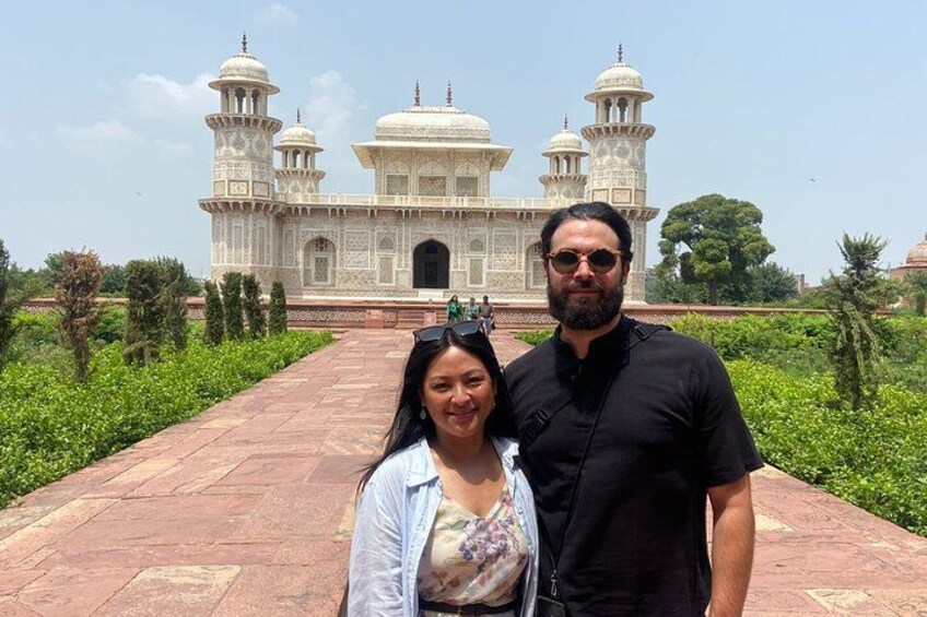 A couple standing in front of a large white marble building with domes and minarets. 2