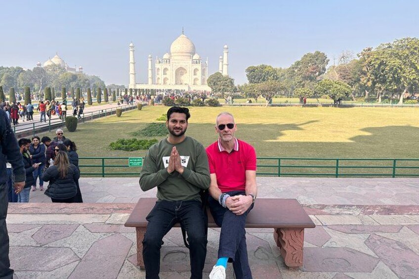 Two people sitting on a bench with the Taj Mahal in the background. 4
