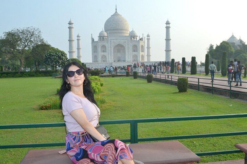 A person sitting on a bench with the Taj Mahal in the background. 2