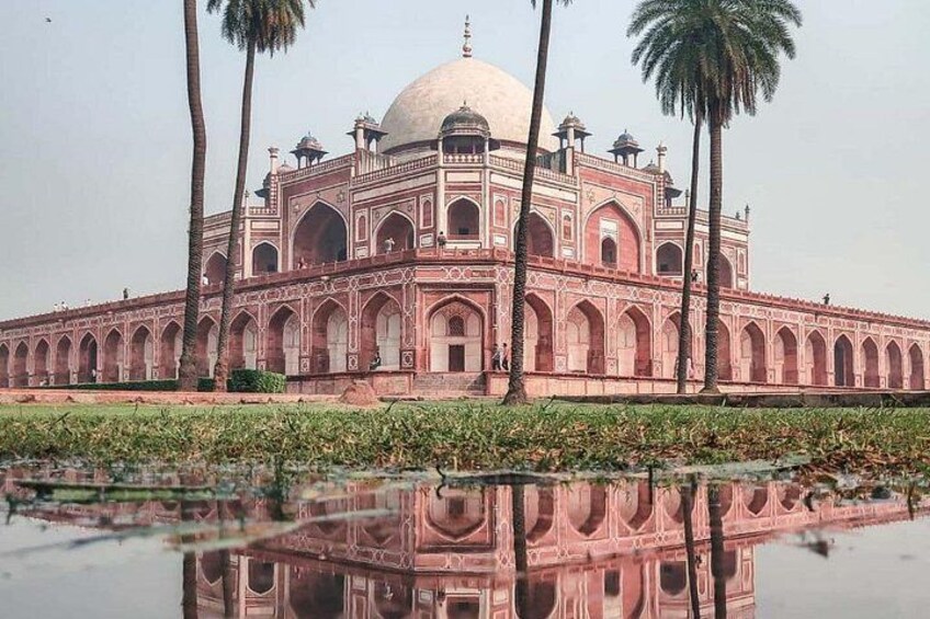 A large, pinkish-red building with a dome and arched windows, surrounded by water and palm trees. 3