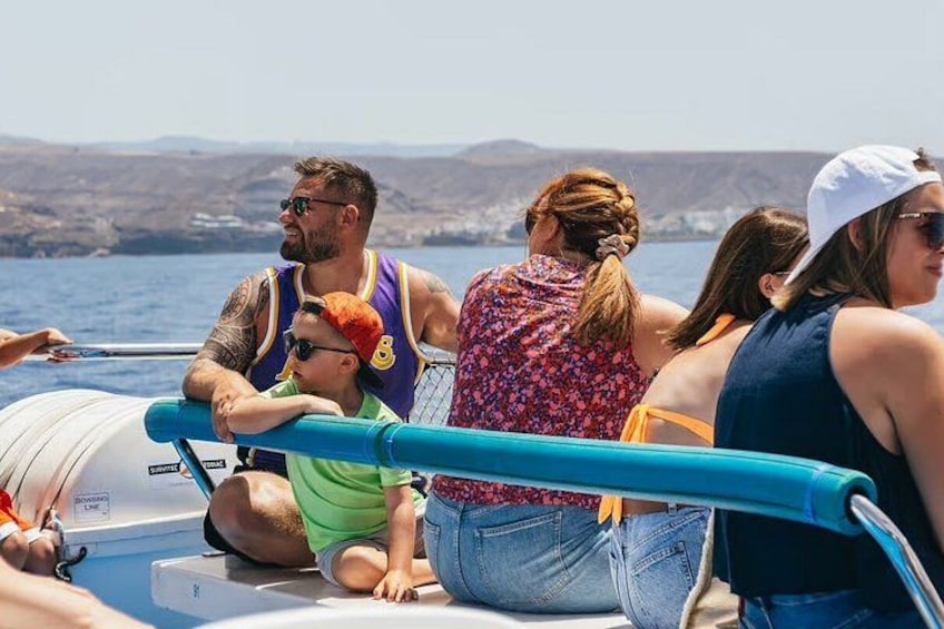 People on a boat with a clear view of the sea and distant land. 2