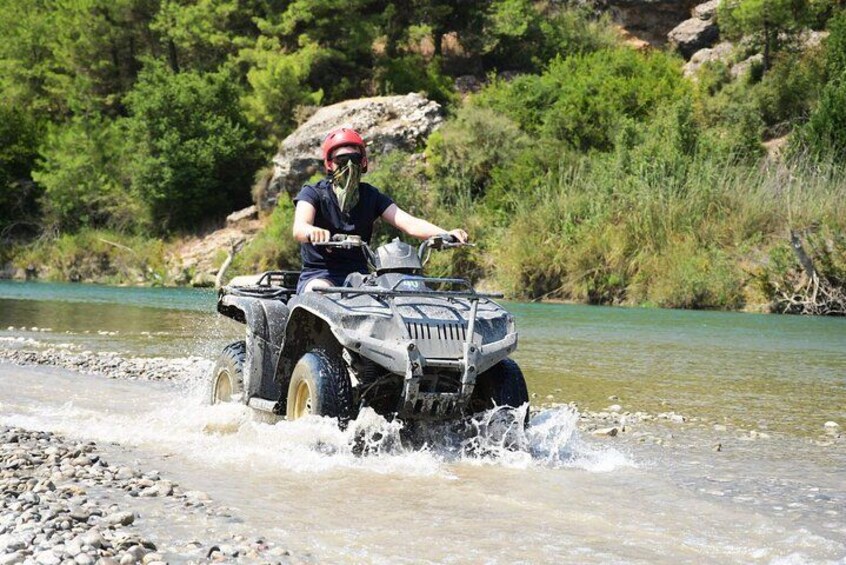Une personne conduisant un véhicule tout-terrain dans une rivière peu profonde. 3