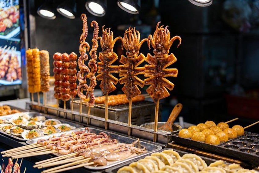 A variety of skewered foods, including octopus and other seafood, displayed at a food stall. 3
