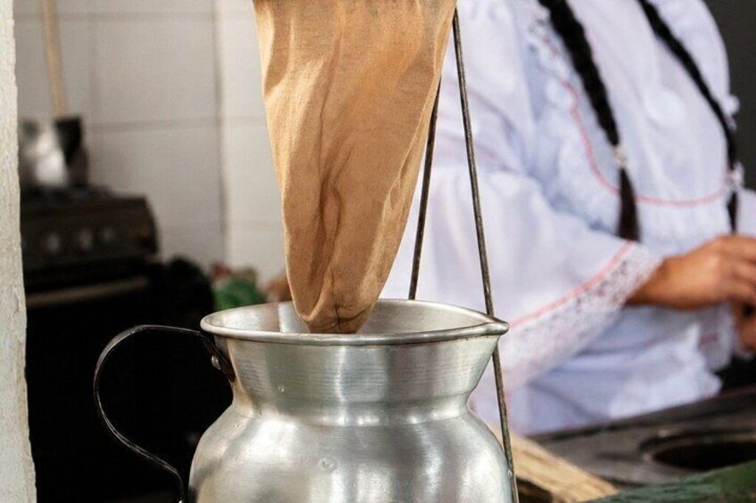 A person straining a liquid through a cloth into a metal container. 5
