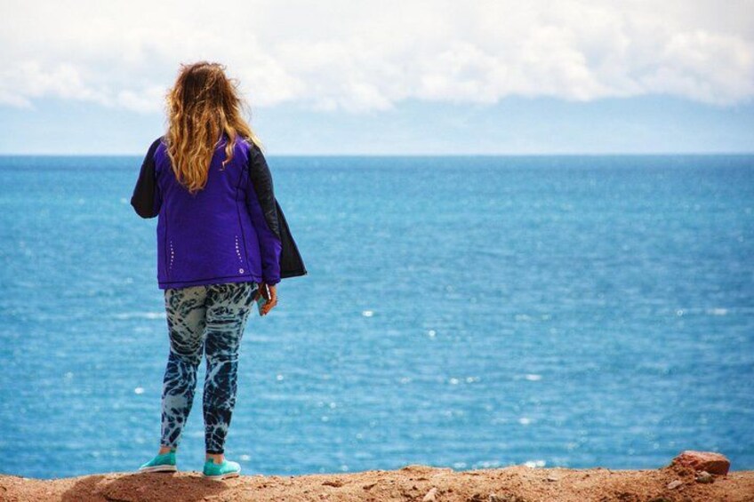 A person standing on a rocky outcrop overlooking the ocean. 5