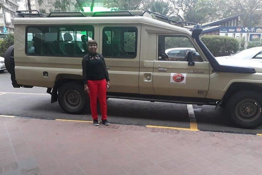 Un SUV beige estacionado en una calle de la ciudad, con una persona a su lado. 5