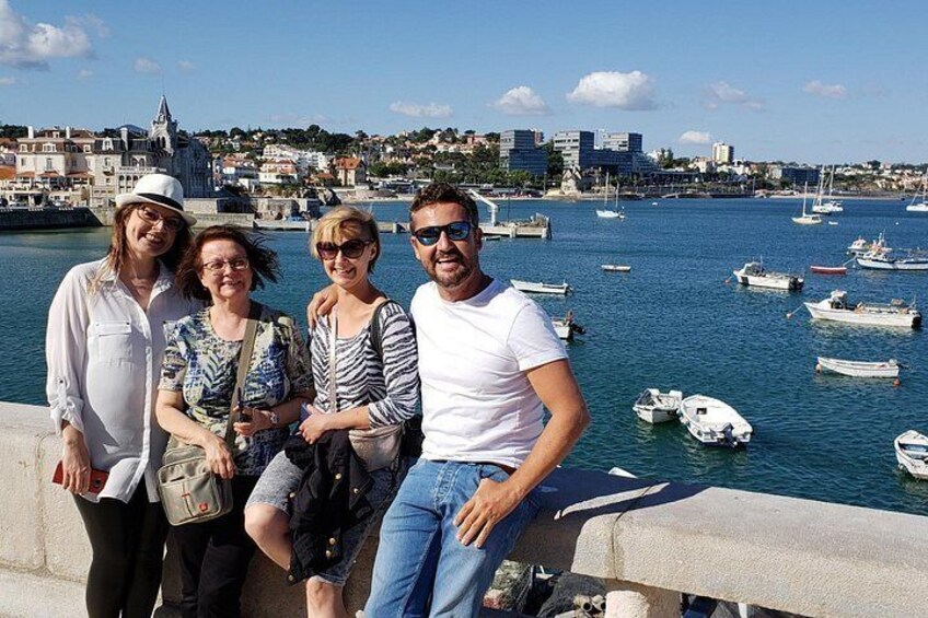 A group of people standing by a waterfront with boats in the background. 3
