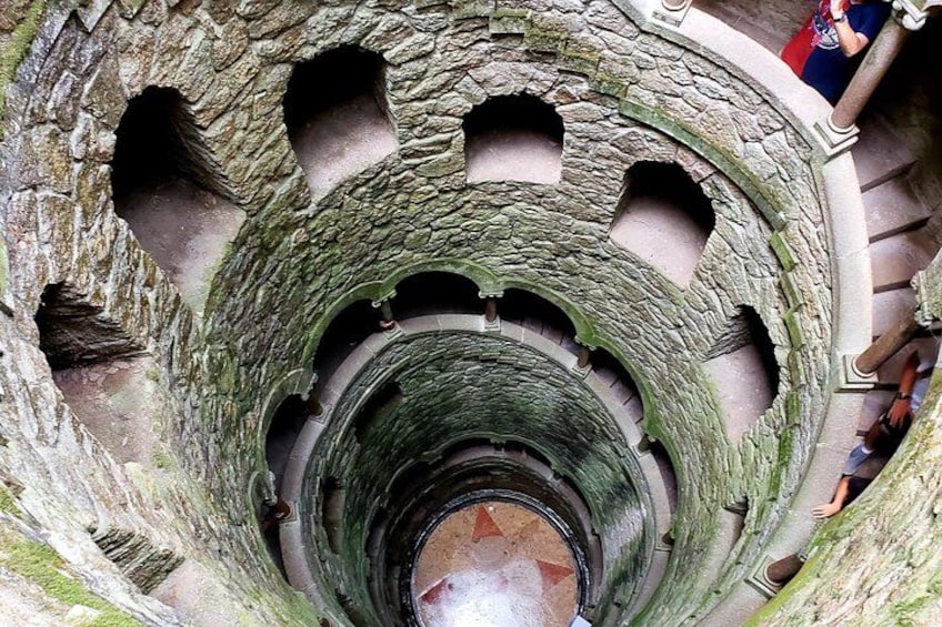 Una escalera en espiral dentro de una construcción de piedra con musgo. 1