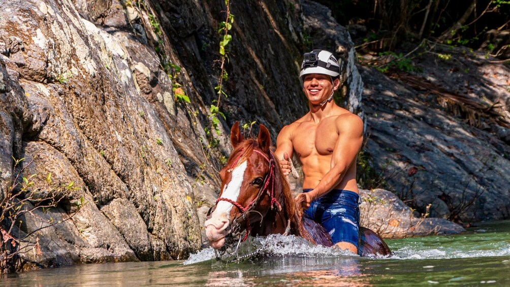 Man riding a horse through a deep river 