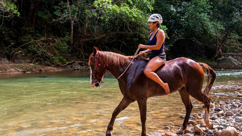 Woman crosses river on horseback