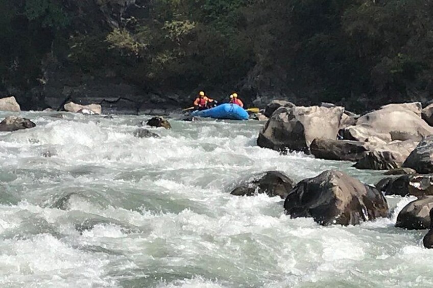 Un fiume con rapide, rocce e una persona su una zattera blu. 4
