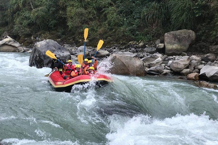 Un gruppo di persone su una zattera rossa che scende un fiume con rapide, circondati da rocce e vegetazione. 3
