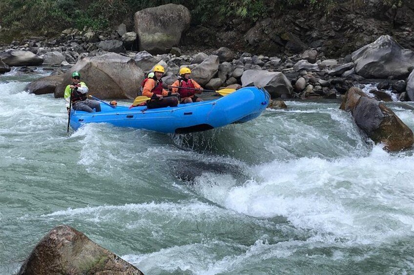Una zattera gonfiabile blu che scende lungo un fiume impetuoso, tra grandi rocce e massi. 5