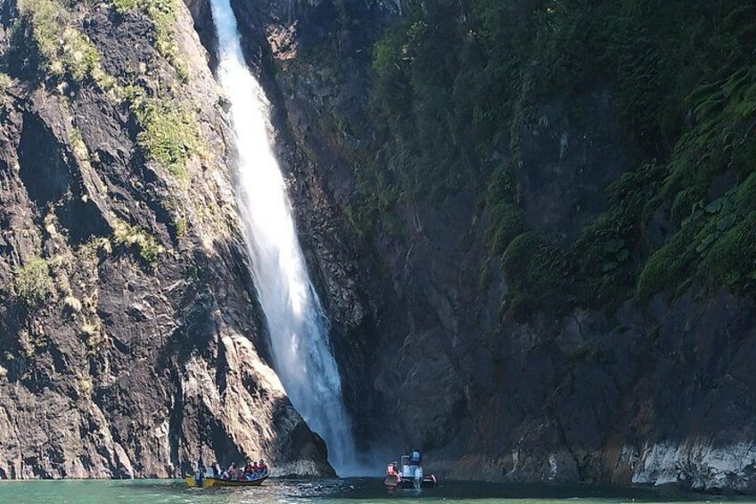 Ein Wasserfall, eine felsige Klippe und ein Boot mit Personen. 2