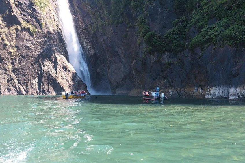 Ein Wasserfall, ein Boot und eine steile Felswand. 3