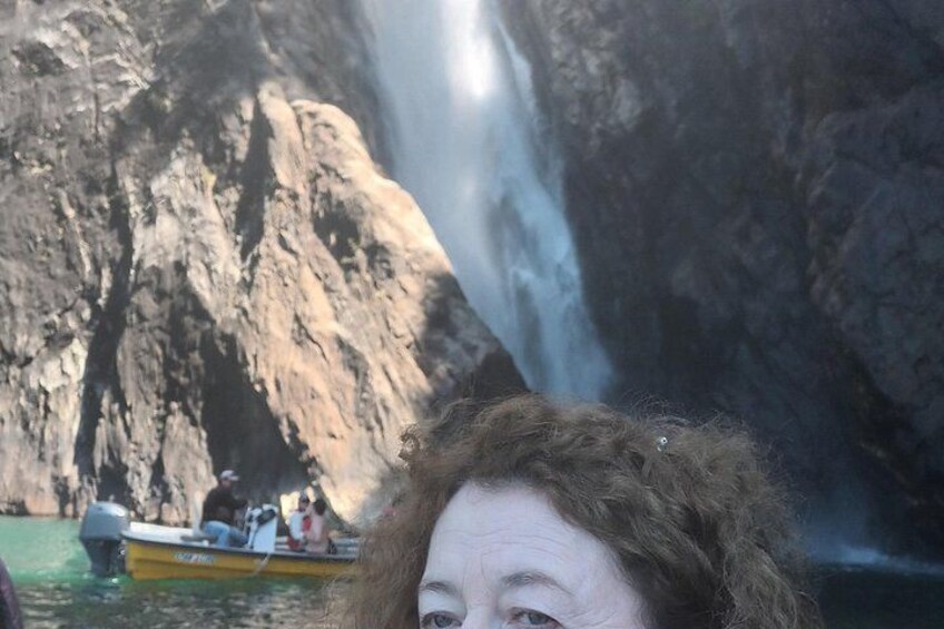 Ein Wasserfall, eine felsige Klippe und ein Boot mit Personen. 5