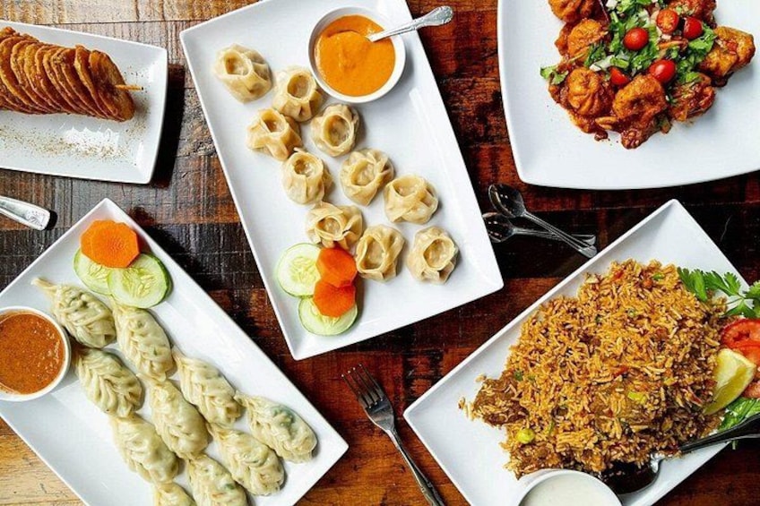 A variety of dishes including dumplings, rice, and a meat dish, served on white plates with garnishes. 5