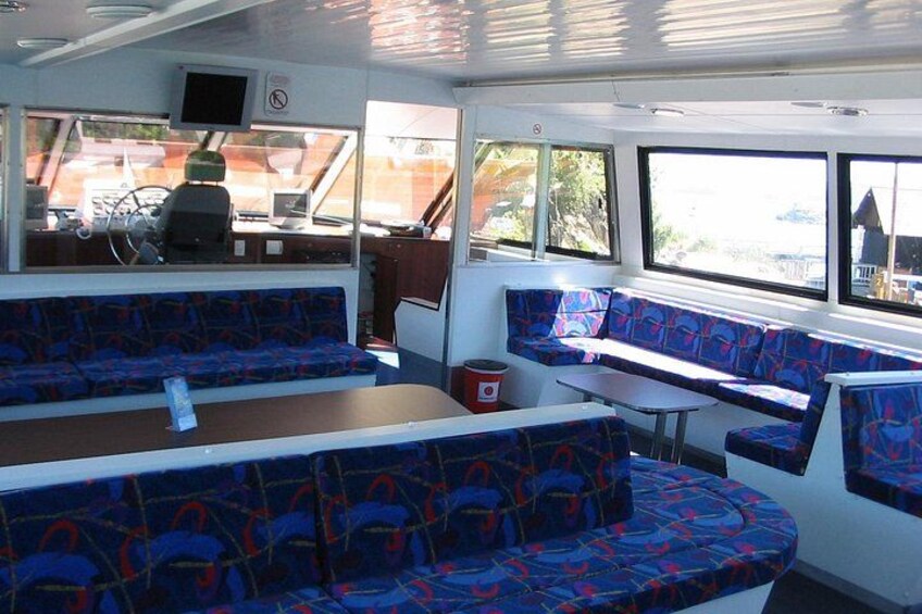 Bootinterieur met blauwe gestreepte zittingen, een stuurwiel en een klein tafeltje. 3
