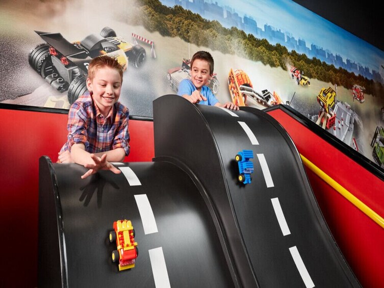 Niños jugando en una pista de carreras con coches de juguete. 1
