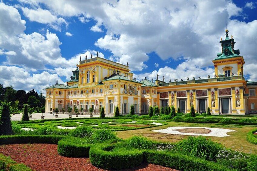 A grand palace with manicured gardens and a clear blue sky. 1