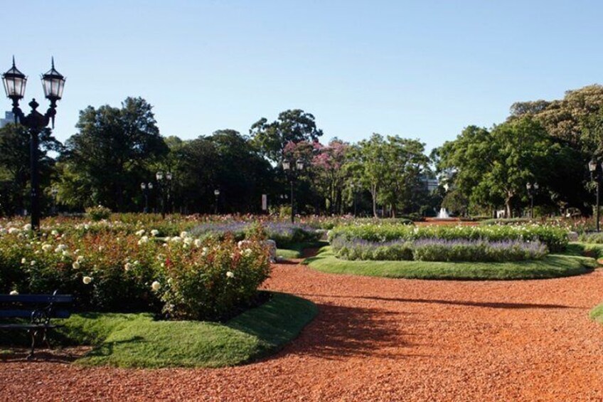 A park with flower beds, a paved path, and trees. 5