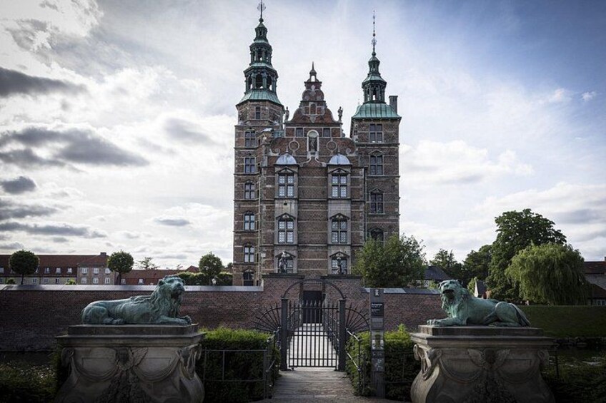 A historic building with two towers, a statue of a lion, and a wrought iron gate. 4