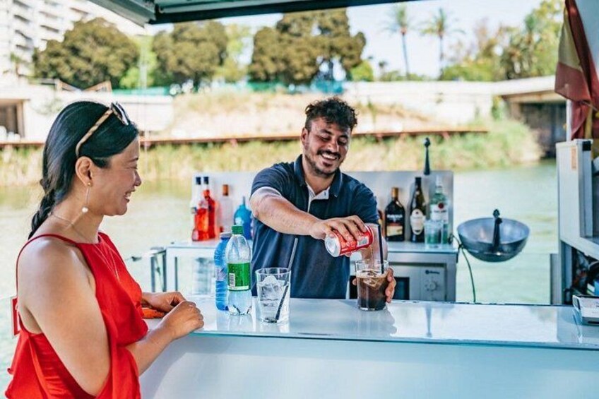 Una persona sirviendo una bebida en un bar con un río al fondo. 3