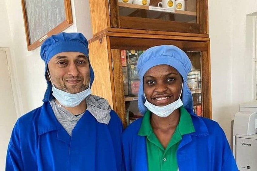 Due persone con camici blu da lavoro e una maglietta verde in una stanza con un armadio in legno e una stampante Canon. 4