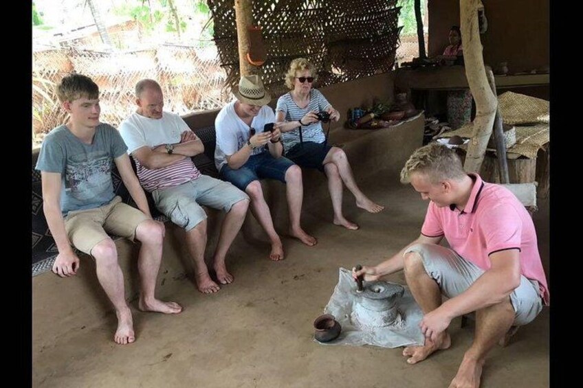 Un groupe de personnes est assis sur un banc à l’extérieur, et l’une d’entre elles travaille sur un tour de potier. 3
