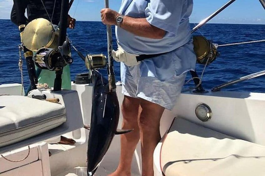A person on a boat holding a fishing rod, with a compass and other navigation equipment visible. 3