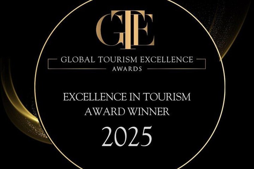 Una placa de premio circular con el texto 'GLOBAL TOURISM EXCELLENCE AWARDS' y 'GANADOR DEL PREMIO DE EXCELENCIA EN TURISMO 2025'. 2