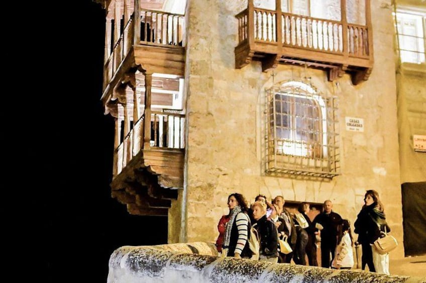 A group of people standing on a stone ledge in front of a building with a balcony. 3