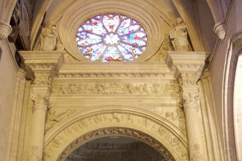 An ornate architectural archway with a stained glass window above. 1