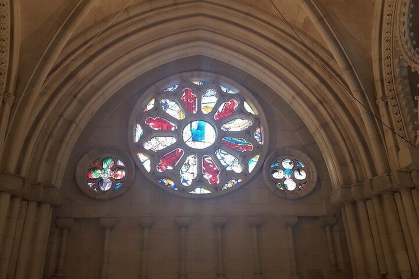 A large stained glass window with intricate designs and smaller circular windows below it. 3