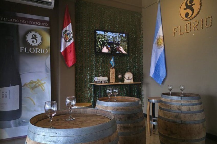 A bar with wooden barrels, a TV screen, and flags of Argentina and Chile. 3