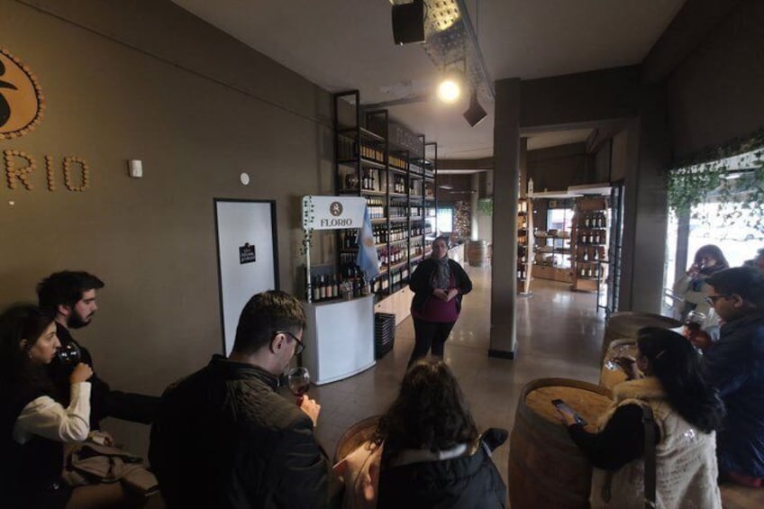 A group of people in a modern indoor setting with shelves of bottles, a refrigerator, and a person walking. 4