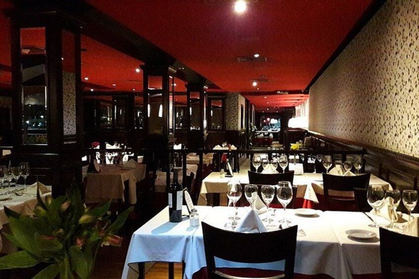 A restaurant interior with tables set for dining, chairs, and a red ceiling. 4