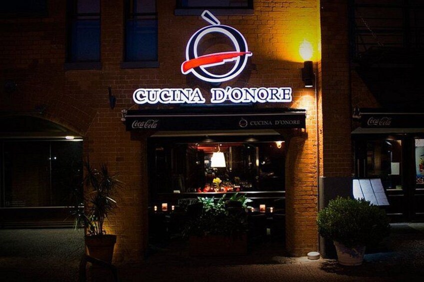 A restaurant named 'Cucina Donore' with a neon sign, outdoor seating, and potted plants. 3